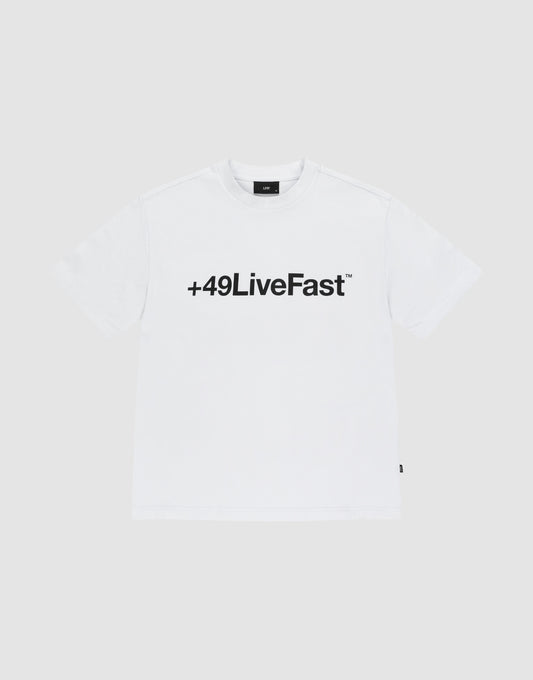 The Basic +49 Tee by LIVE FAST DIE YOUNG features a bold black “+49LiveFast™” front print on white, made from 100% Baumwolle, shown against a plain light grey background.