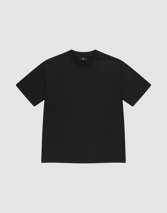 The LIVE FAST DIE YOUNG Basic Heavy Tee, a plain black short-sleeve shirt made from 100% Baumwolle, is shown laid flat on a light gray background with a classic crew neck and no visible logos or designs. | plain