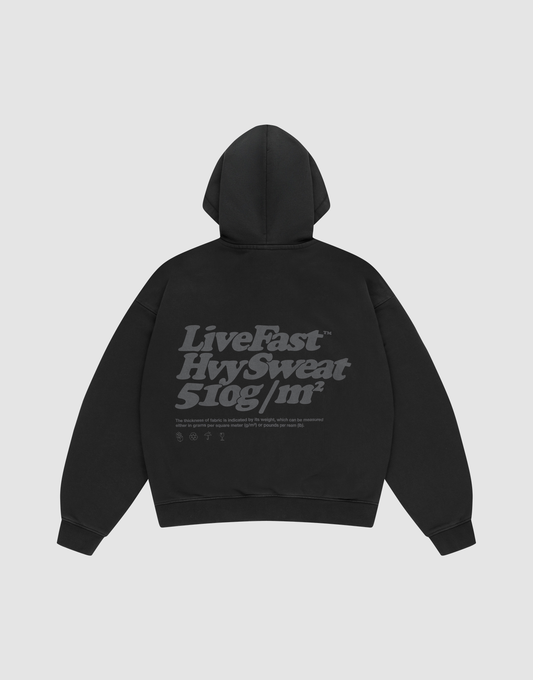 The Basic 510 Hooded Zip by LIVE FAST DIE YOUNG, in black Oversize Fit, is laid flat showing the back with bold gray "Live Fast. Hvy Sweat. 510g/m²" text plus smaller details, all on a plain light gray background.