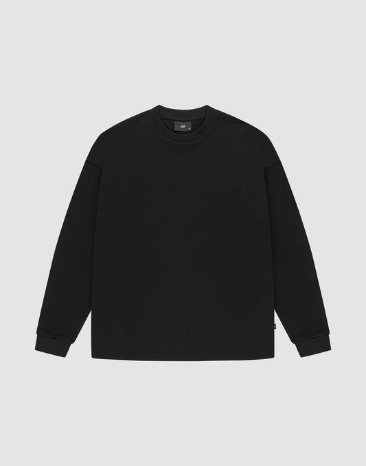 The LIVE FAST DIE YOUNG Blank Waffle Longsleeve, a black oversized crewneck sweatshirt made from 100% Baumwolle, features Ripp-Bündchen at the cuffs and neckline and is shown laid flat on a light gray background. | plain