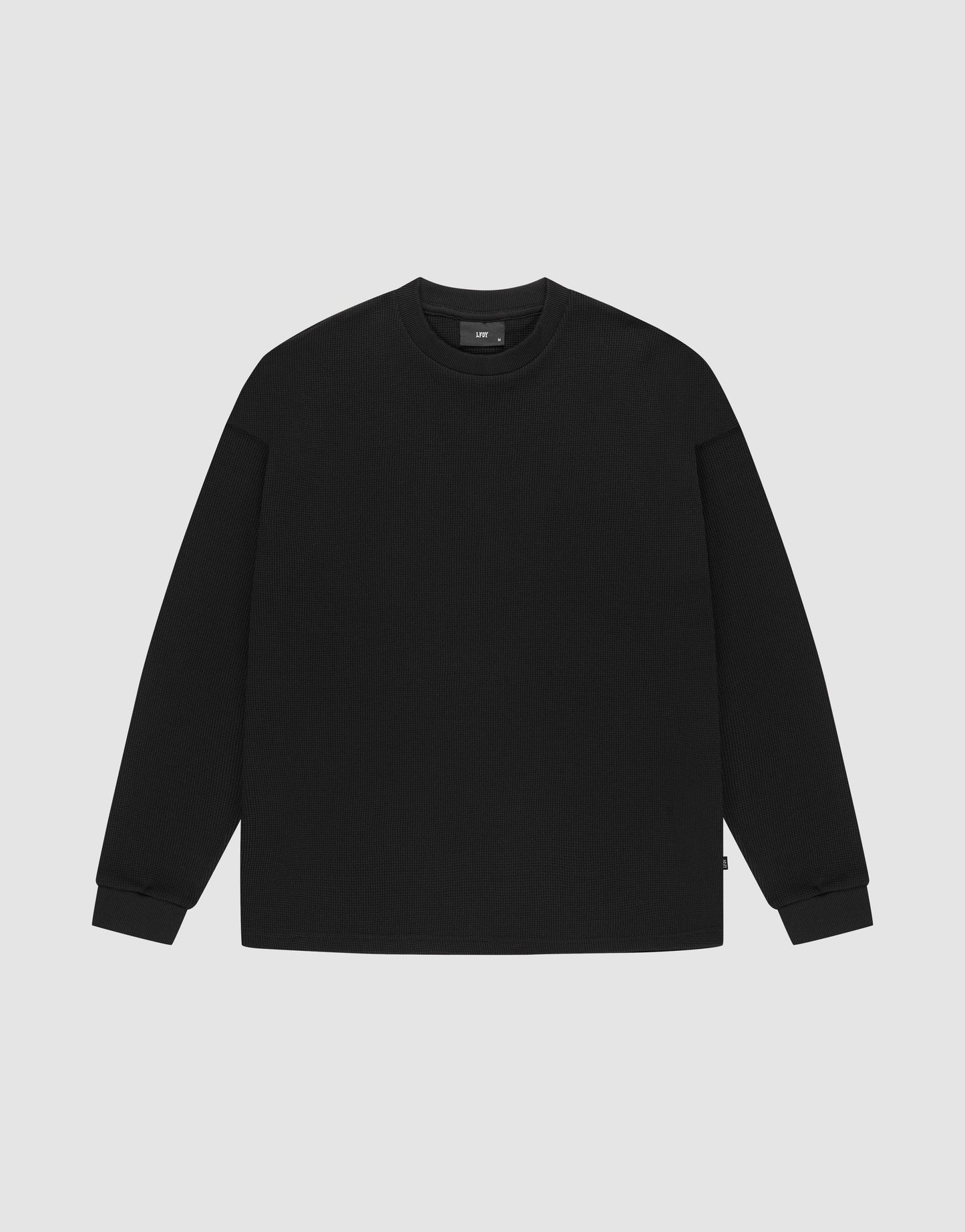 The LIVE FAST DIE YOUNG Blank Waffle Longsleeve, a black oversized crewneck sweatshirt made from 100% Baumwolle, features Ripp-Bündchen at the cuffs and neckline and is shown laid flat on a light gray background. | plain