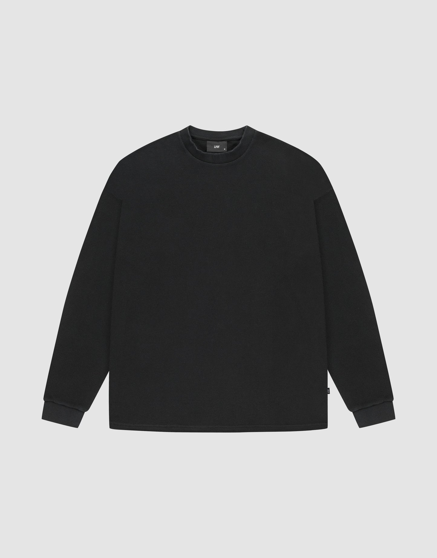 The LIVE FAST DIE YOUNG Blank Waffle Longsleeve is an oversized, plain black crewneck sweatshirt made from 100% Baumwolle, shown on a light gray background. | plain