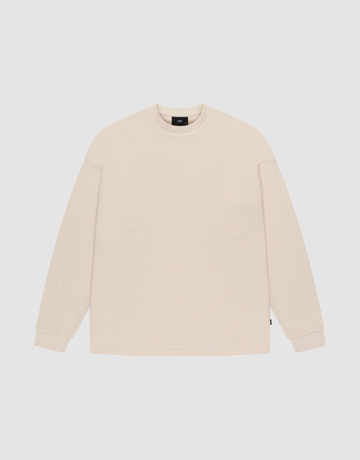 The LIVE FAST DIE YOUNG Blank Waffle Longsleeve is a beige, oversized crewneck with long sleeves and ribbed cuffs, made from 100% Baumwolle. It’s shown laid flat on a white background.