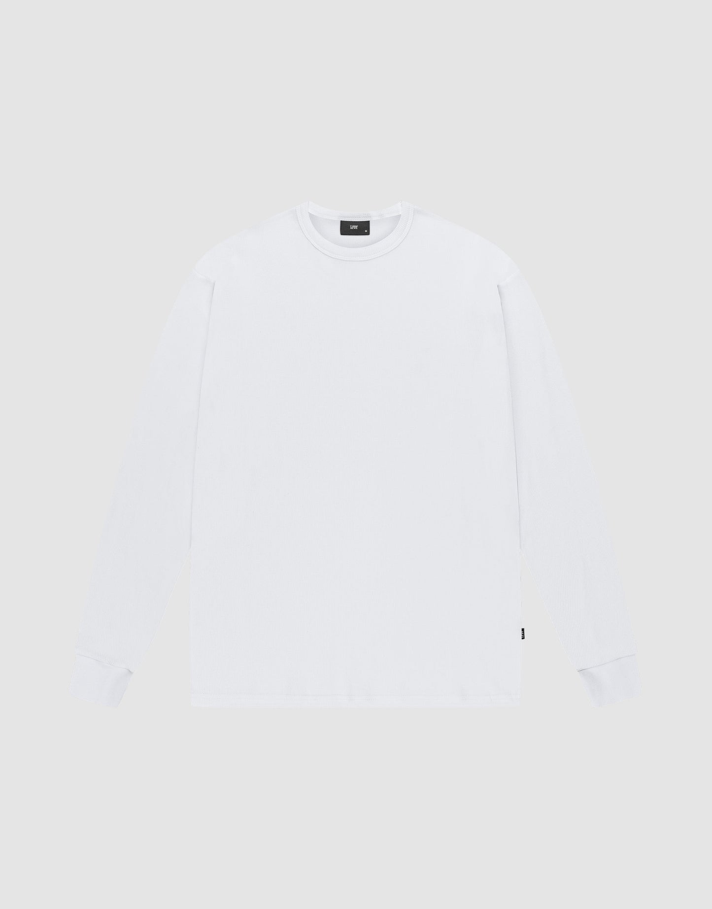 The LIVE FAST DIE YOUNG Blank Waffle Longsleeve is a white, oversized, crewneck shirt made from 100% Baumwolle. Laid flat on a light gray background, it features a small black flag-label on the lower side seam and no visible logos or designs. | plain