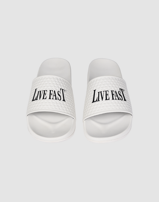 The LFDY Slides by LIVE FAST DIE YOUNG feature white PU textured straps with “LIVE FAST” in bold black letters, a comfortable EVA sole, and model number LF2606-20682.