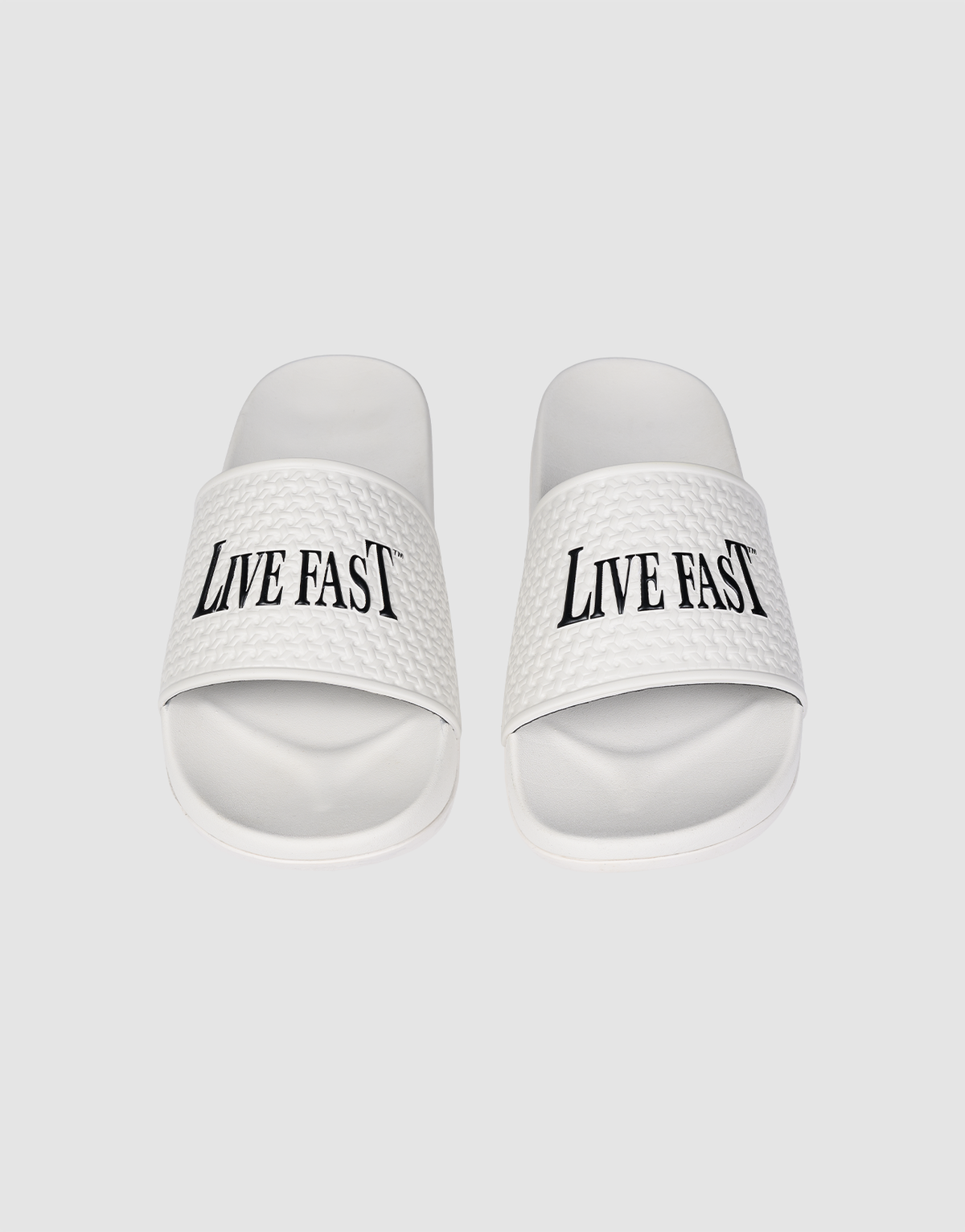 The LFDY Slides by LIVE FAST DIE YOUNG feature white PU textured straps with “LIVE FAST” in bold black letters, a comfortable EVA sole, and model number LF2606-20682.
