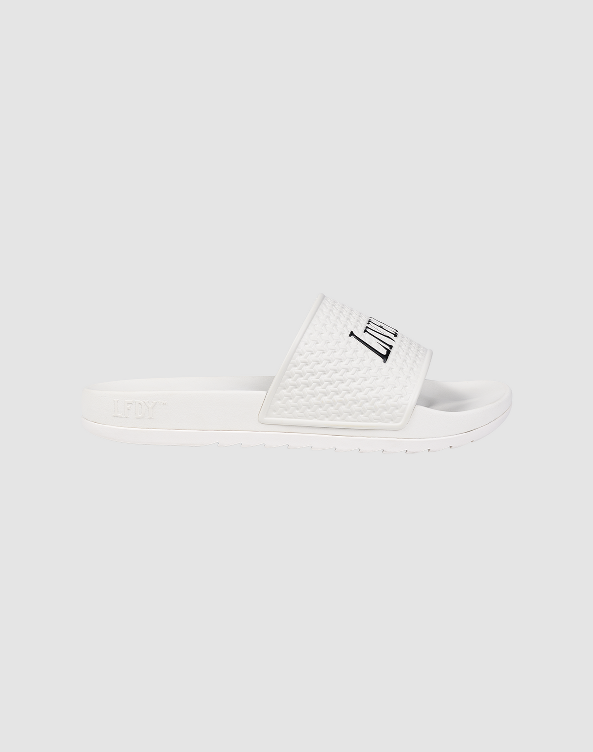 The LFDY Slides by LIVE FAST DIE YOUNG feature a white slip-on design with a textured PU strap, "LFTY" in black, and a comfy EVA sole. Shown on a light gray background. Style code: LF2606-20682.