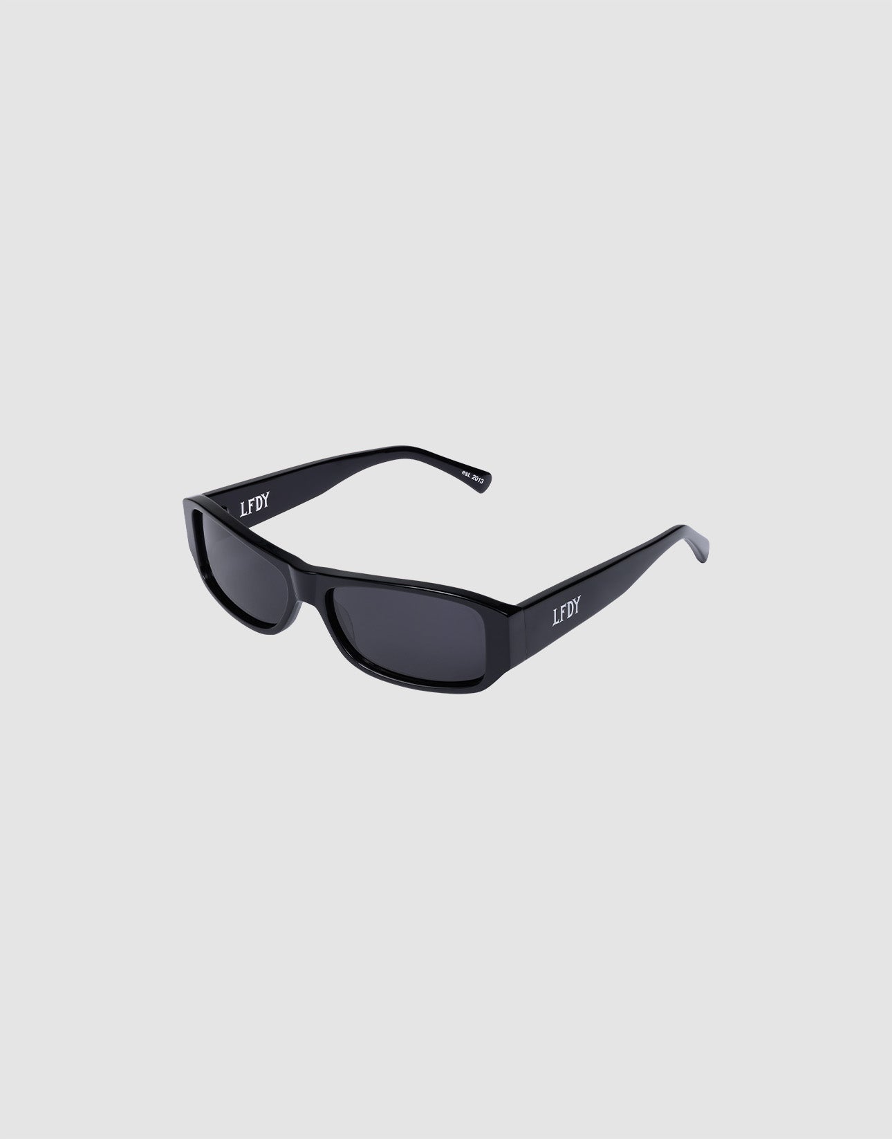 The LFDY Wrap by LIVE FAST DIE YOUNG is a pair of black rectangular sunglasses with dark UV-protection lenses and "LFDY" in white on the arms. Shown against a plain light gray background.