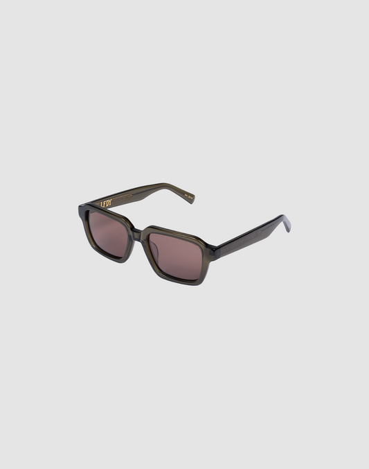 The LFDY Forma by LIVE FAST DIE YOUNG features rectangular sunglasses with thick, dark translucent frames, brown-tinted lenses, gold lettering on the left arm near the hinge, and facettenschliffe detailing for subtle elegance.