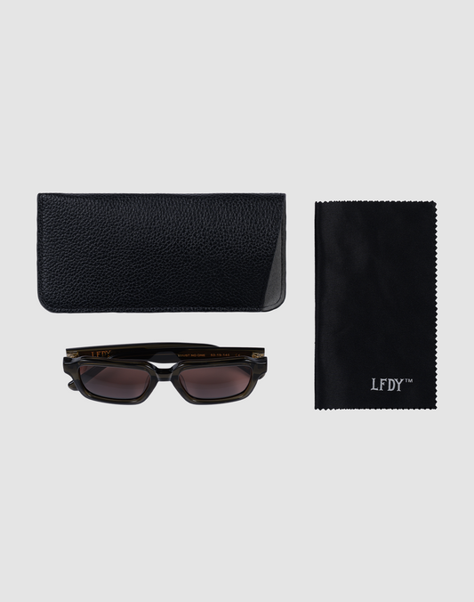The LFDY Forma sunglasses by LIVE FAST DIE YOUNG, featuring facettenschliffe, come with a black textured case and an LFDY™ Reinigungstuch, all arranged on a light grey background.