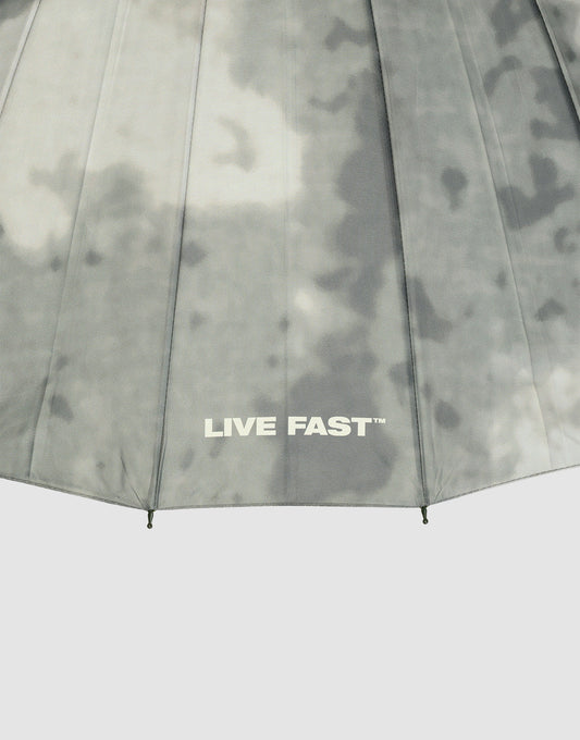 A close-up of the LFDY Umbrella by LIVE FAST DIE YOUNG, featuring a grey cloudy pattern, stabile Rahmenkonstruktion, and “LIVE FAST™” printed in white near the bottom edge.