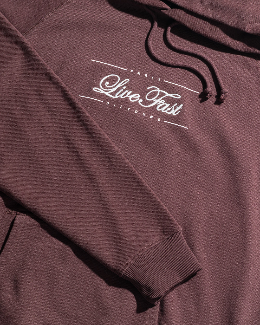 The LFDY Embroidery Hooded by LIVE FAST DIE YOUNG is a maroon regular fit hoodie in 100% Baumwolle French Terry, featuring a front pocket, drawstrings, and white "PARIS Live Fast DIE YOUNG" text on the chest.
