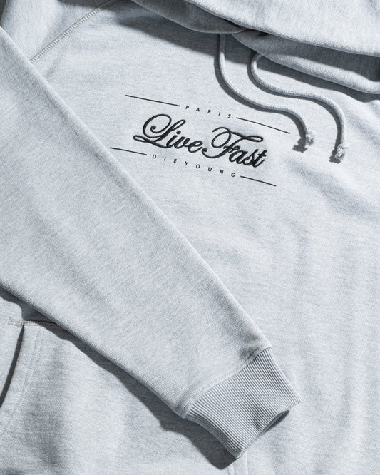 The LFDY Embroidery Hooded by LIVE FAST DIE YOUNG is a light gray regular fit hoodie with raglan sleeves, an adjustable hood, front pocket, ribbed cuffs, and black "Paris Live Fast Die Young" text across the chest.