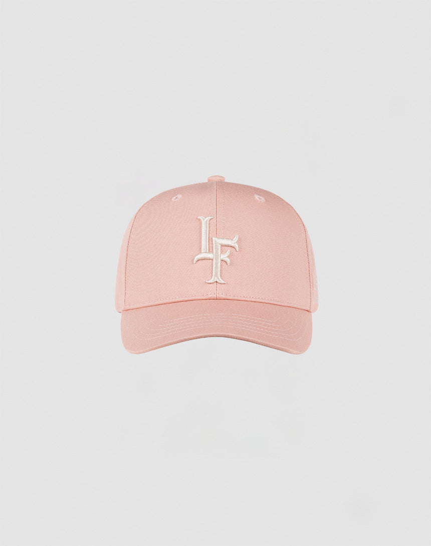 The LF Snapback by LIVE FAST DIE YOUNG is a light pink Baumwolle cap with a curved brim, white embroidered intertwined L and F on the front, and a practical snap closure, shown against a plain light background.