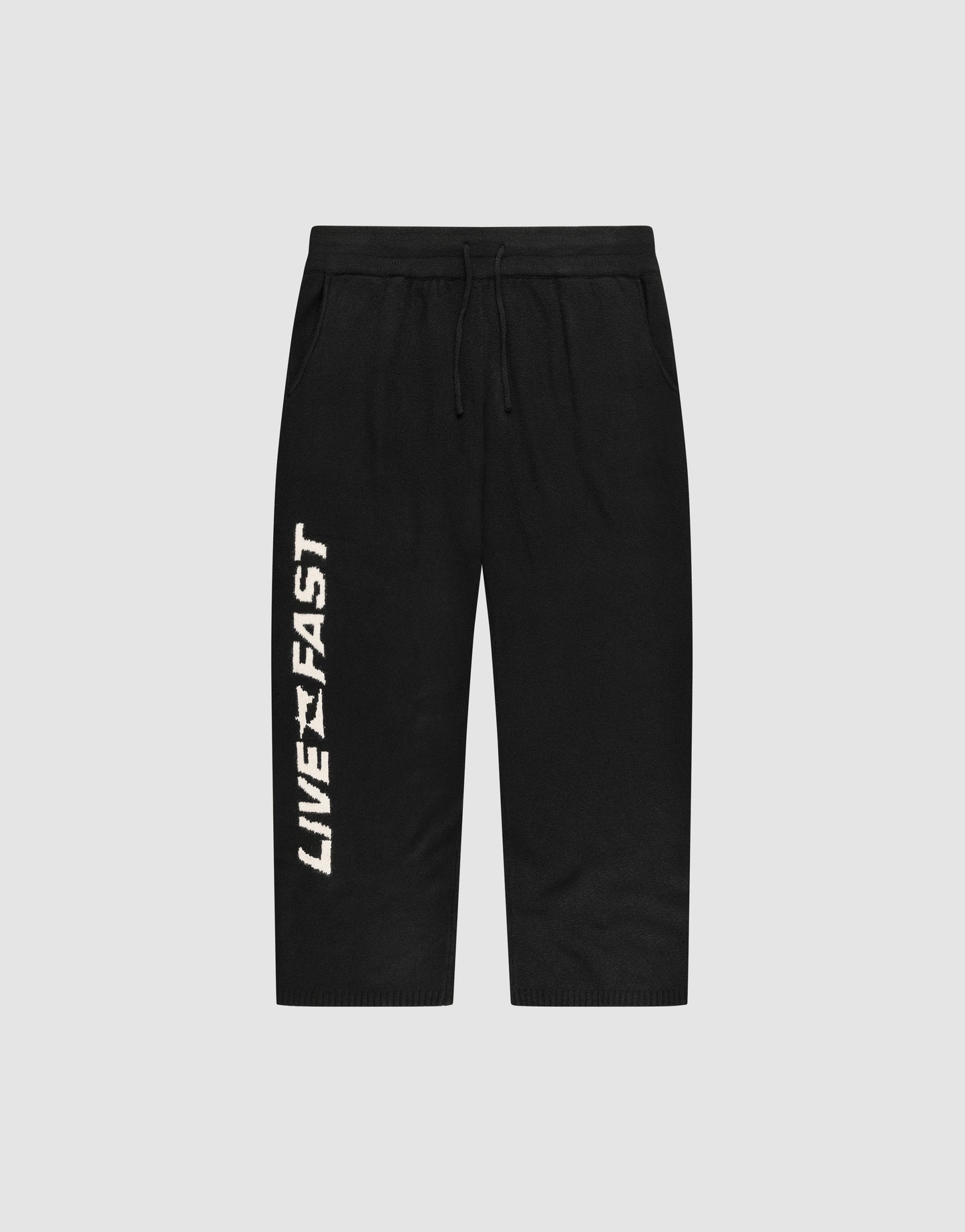 The Live Fast Boucle Pants by LIVE FAST DIE YOUNG feature an Elastik-Bund drawstring waist, a straight leg cut, and bold vertical “LIVE FAST” lettering in white on the left leg. Shown against a plain light gray background.