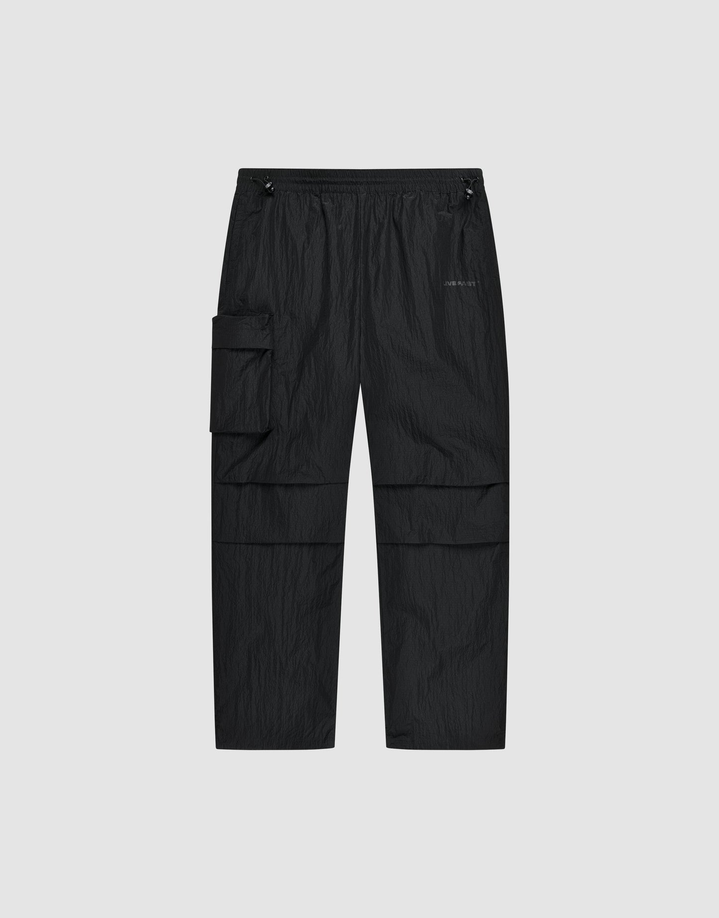 The Live Fast Nylon Pants by LIVE FAST DIE YOUNG feature an elastic waistband, adjustable drawstrings, oversized fit, multiple pockets including a large zip cargo pocket, and a small logo on the left thigh, shown against a light gray background.