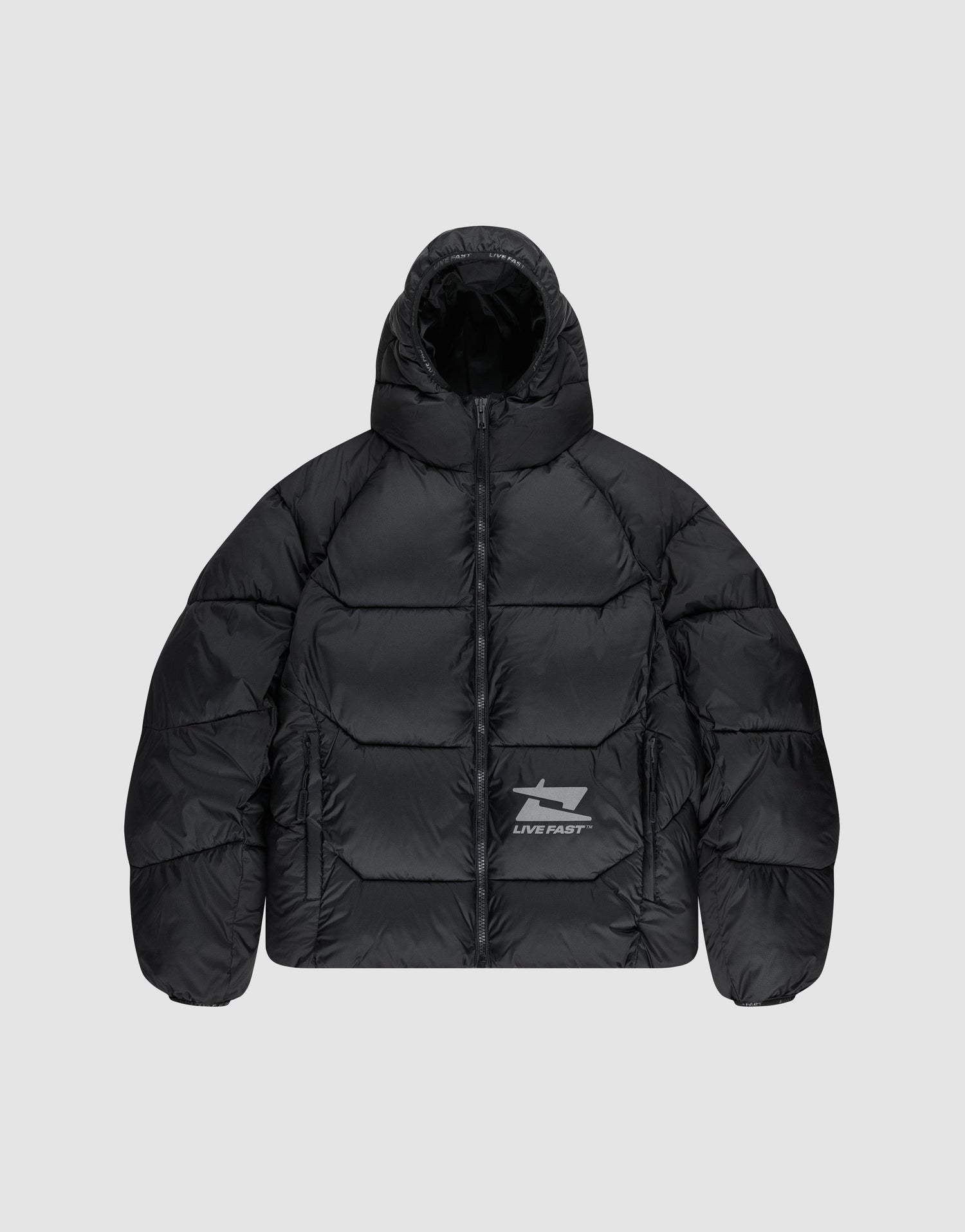 The Live Fast Puffer Jacket by LIVE FAST DIE YOUNG is a black, water-repellent jacket with a hood, front zipper, and reflective "LIVE FAST" text plus a shark graphic on the left chest. Seen here on a light gray background. | plain