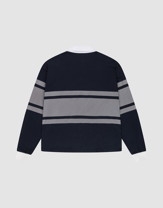 The LFDY Striped Polo by LIVE FAST DIE YOUNG is a navy blue oversize fit long-sleeve shirt with white cuffs and collar, featuring two grey stripes across the back and sleeves. Made from soft cotton twill, it's displayed flat on a light gray background.