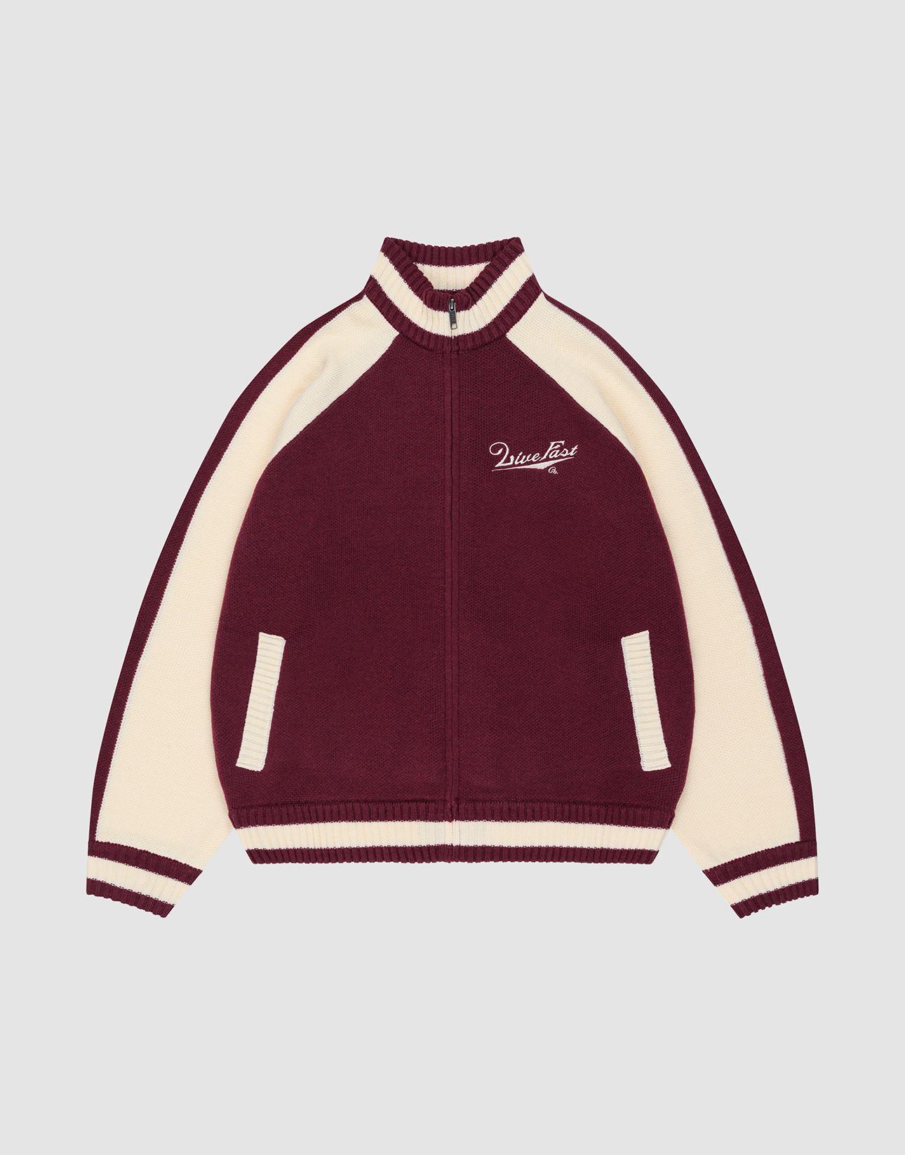 A person faces away, wearing a Boxy Knit Zip Jacket by LIVE FAST DIE YOUNG in burgundy and cream with a horse graphic and "Live Fast" on the back, styled with light blue baggy jeans and white sneakers against a plain background.