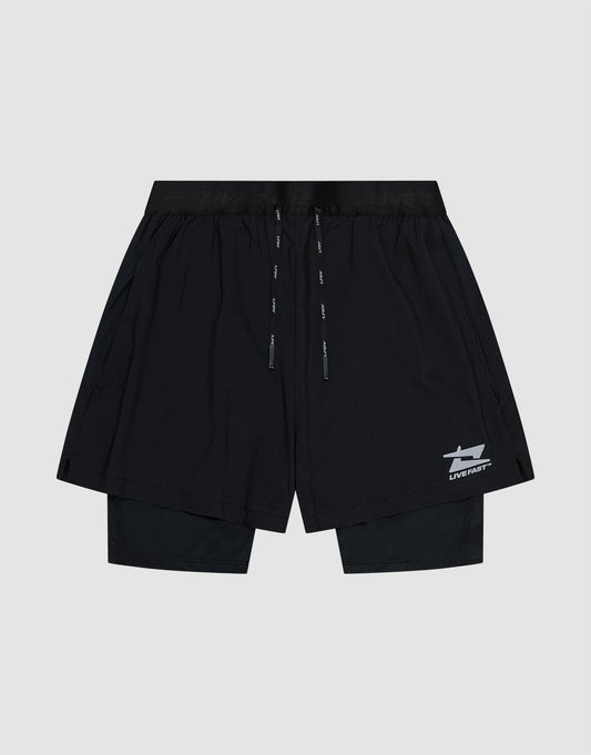 The LIVE FAST DIE YOUNG Live Fast Performance Running Shorts feature an overlapping design with built-in tights, elastic waistband with drawstrings, and a small white Live Fast Branding logo on the lower left leg, shown on a plain light gray background.| plain