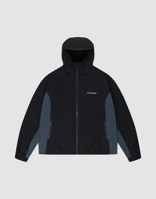The LIVE FAST DIE YOUNG Basic Shell Jacket features an oversize fit, black hood, dark gray panels, front zipper, side pockets, and "LMC PDRF" in small white letters on the left chest. Shown laid flat on a light gray background. | plain