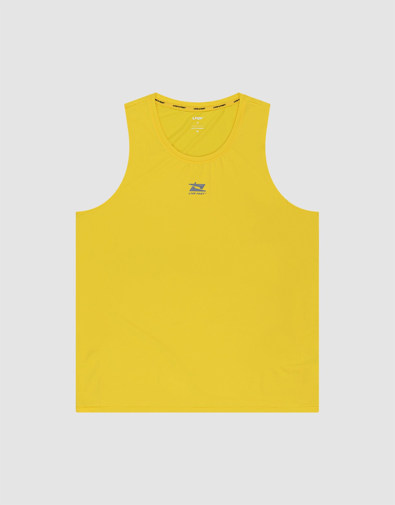 A man stands against a plain gray background wearing the LIVE FAST DIE YOUNG Live Fast Performance Tank in bright yellow and matching shorts with white sneakers, looking down to his left with his hands behind his back.