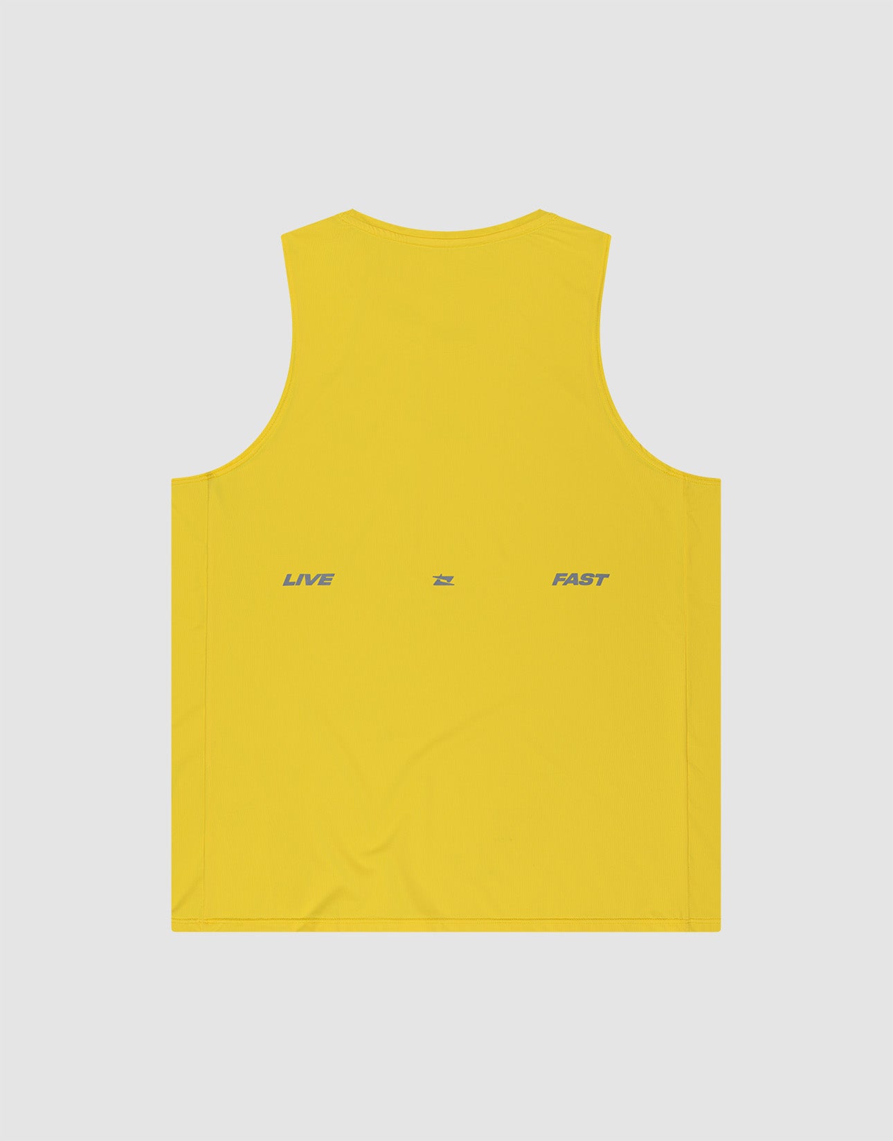 A person with braided hair wears the LIVE FAST DIE YOUNG Live Fast Performance Tank in yellow and matching shorts with reflective LIVE FAST print, plus white socks and sneakers. They face away from the camera with arms crossed against a plain background.