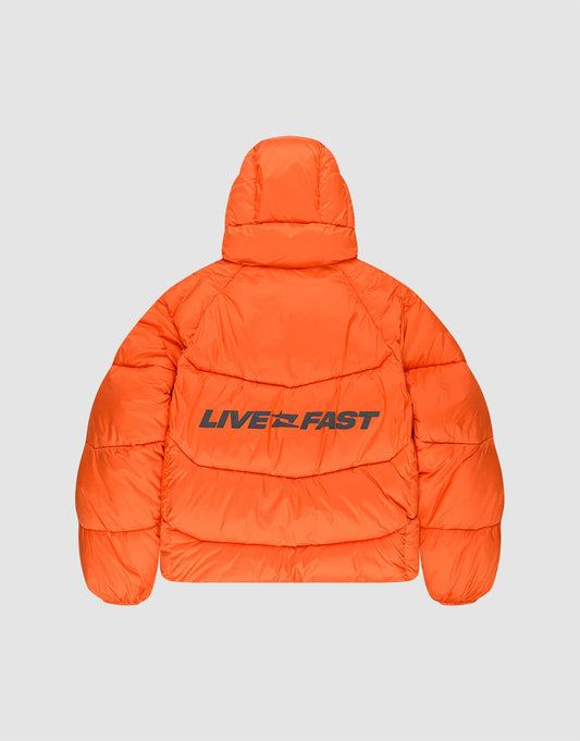 The LIVE FAST DIE YOUNG Live Fast Puffer Jacket is an oversize bright orange puffer with a hood, featuring the bold black reflective “LIVE FAST” print across the back.