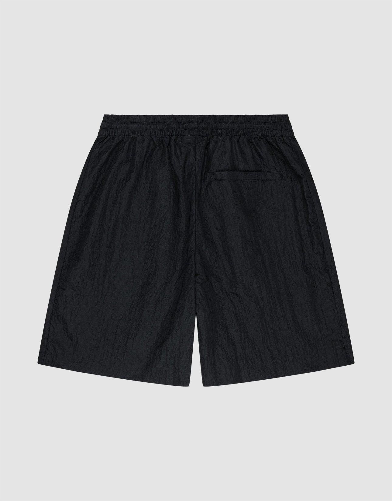 LIVE FAST DIE YOUNG’s Live Fast Nylon Shorts in black feature an oversized fit, an elastic waistband, and a single back pocket. Shown flat on a light gray background with the back view visible.