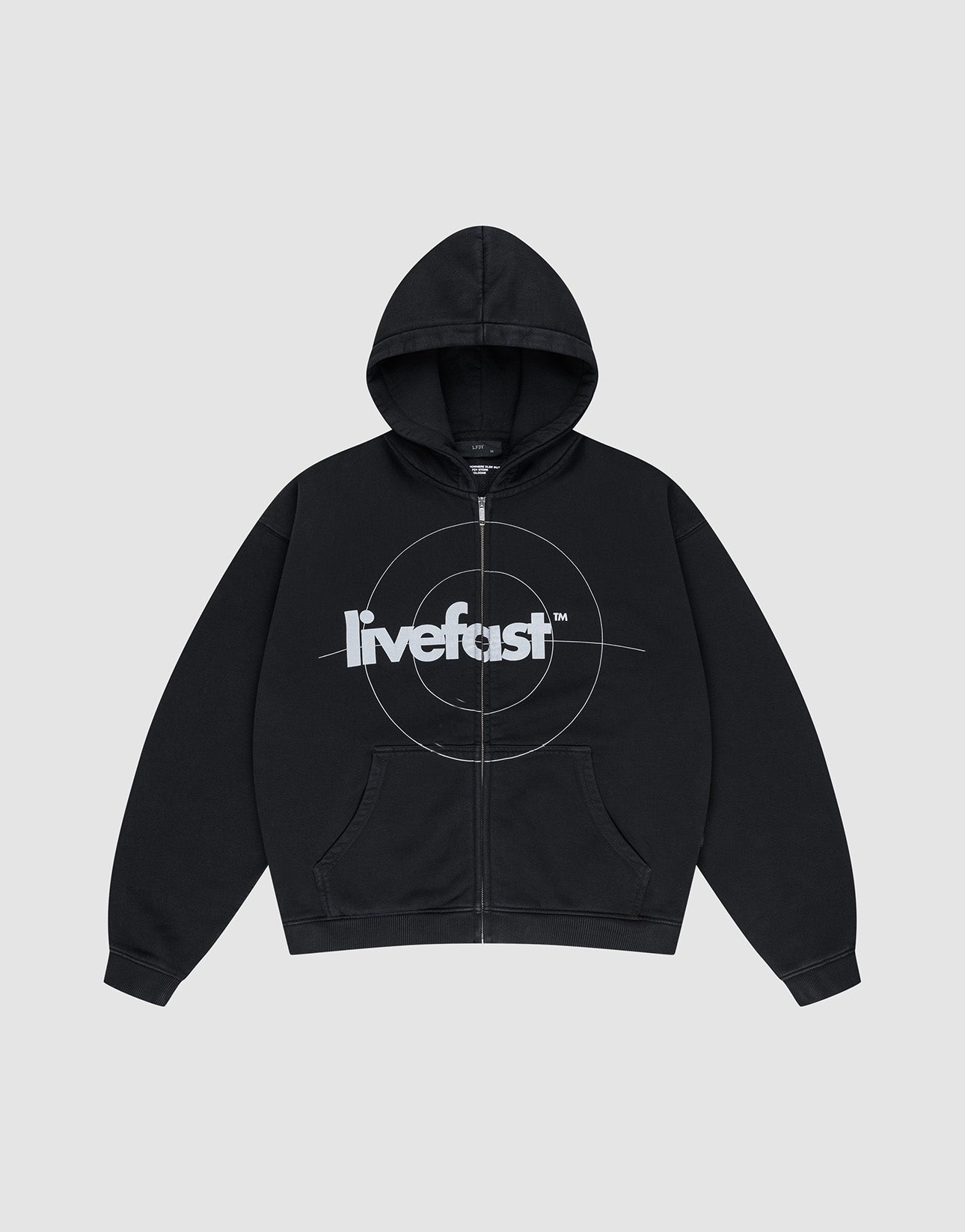 The LIVE FAST DIE YOUNG Live Fast Target Hooded Zip is a black oversized hoodie with front pockets, a hood, and bold "livefast" text over a circular chest design, displayed on a plain light gray background.| plain