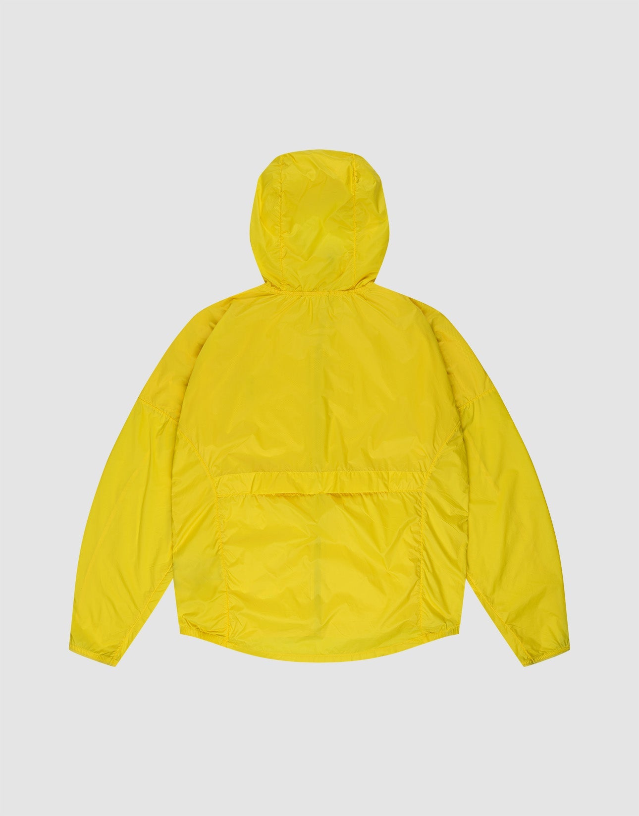 A man stands against a plain background wearing the bright yellow Live Fast Performance Running Jacket by LIVE FAST DIE YOUNG with reflektierender Frontprint, matching shorts, white socks, and white sneakers. Hands in pockets, he looks at the camera.