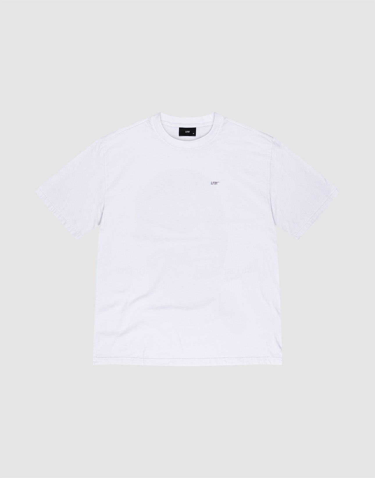 A man faces away, wearing the LFDY Originals Tee by LIVE FAST DIE YOUNG—a white oversize Baumwolle shirt with a bold purple backprint portrait—paired with purple shorts, white LIV socks, and white sneakers against a plain light background.