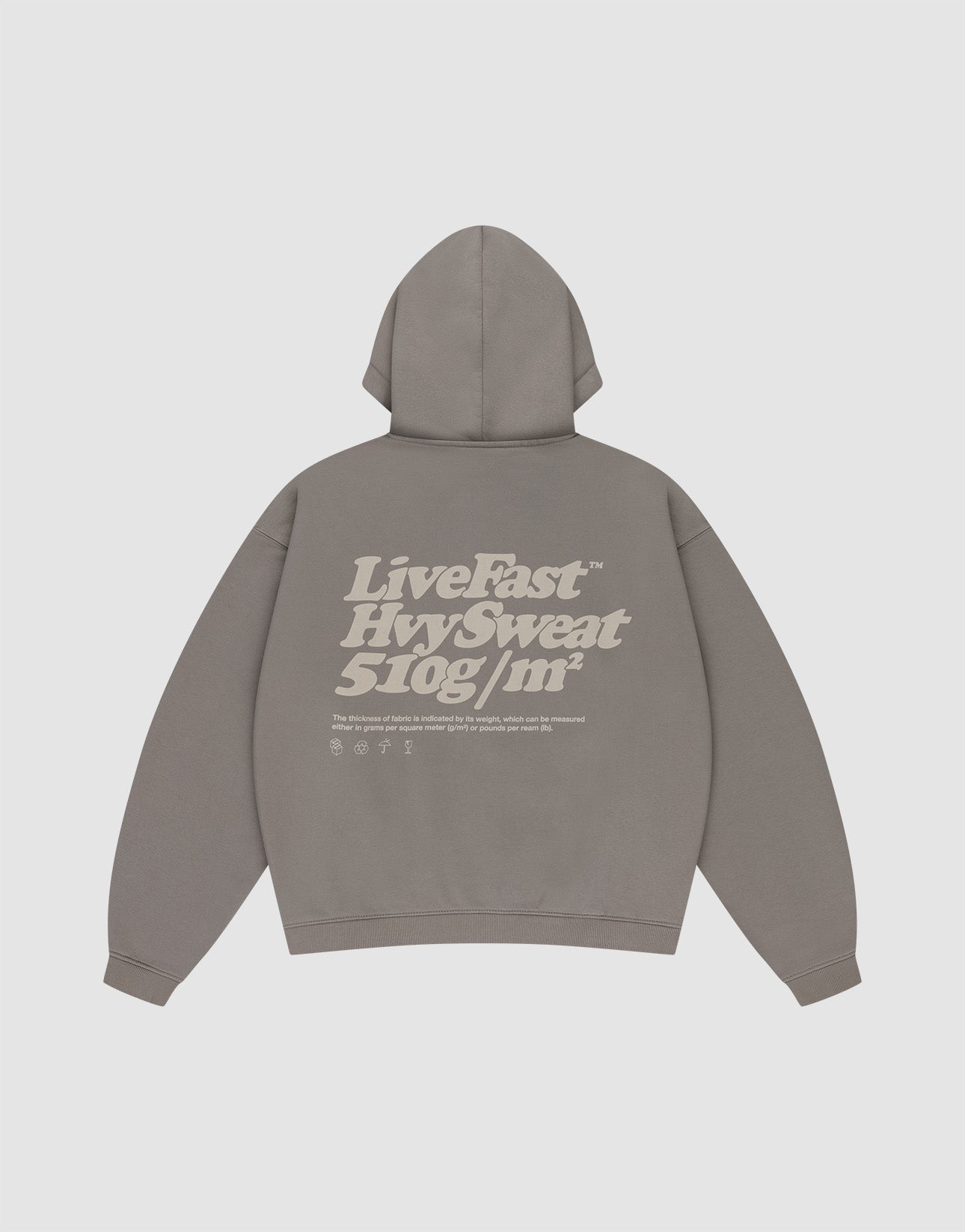 A person faces away, wearing the LIVE FAST DIE YOUNG Basic 510 Hooded Zip—an oversize gray hoodie with front and back prints—paired with light blue baggy jeans, a dark patterned headscarf, and white shoes against a plain background.