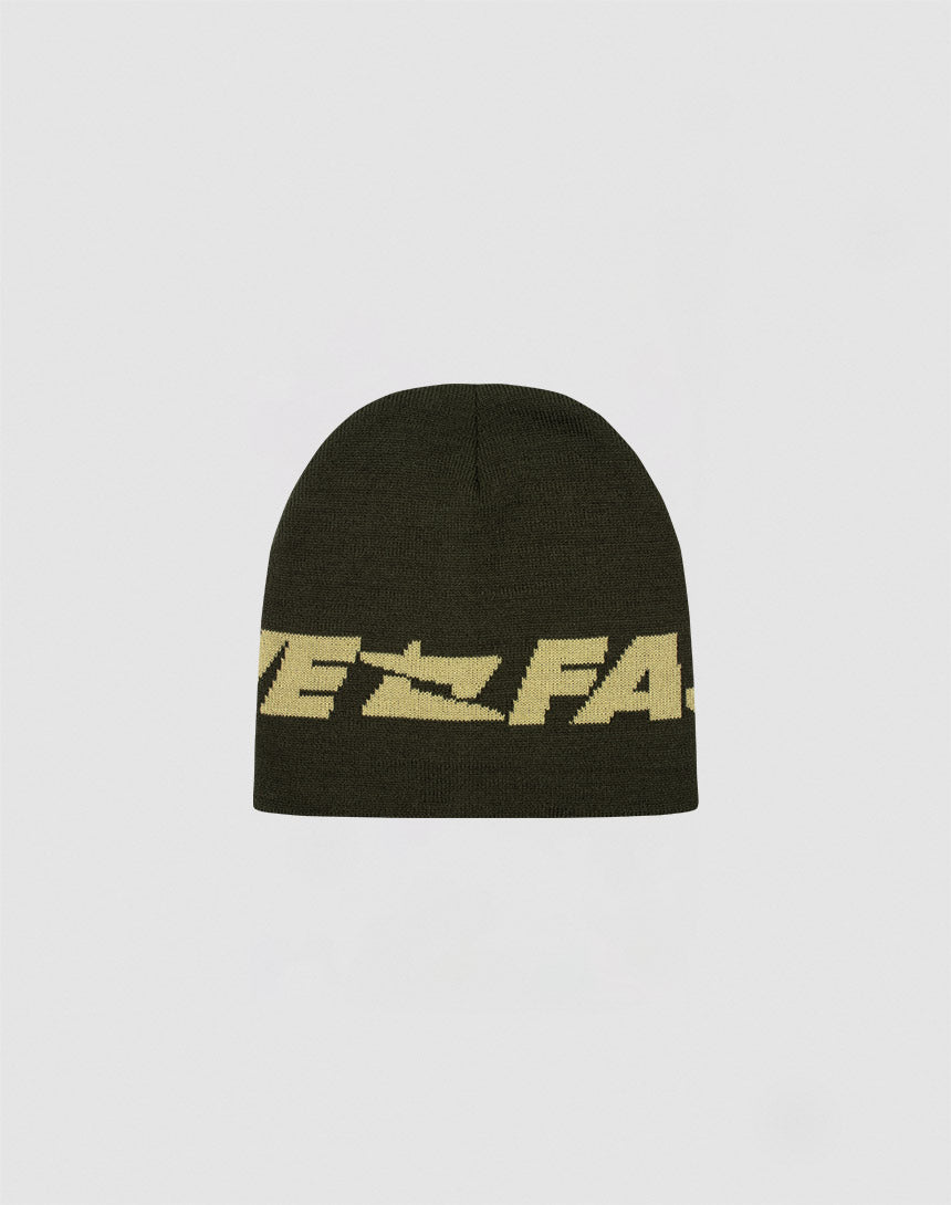 The LIVE FAST DIE YOUNG Live Fast Jacquard Beanie is a dark olive green Polyacryl knit hat featuring bold yellow Logo Strick lettering and a zigzag design around the middle, shown against a plain white background.