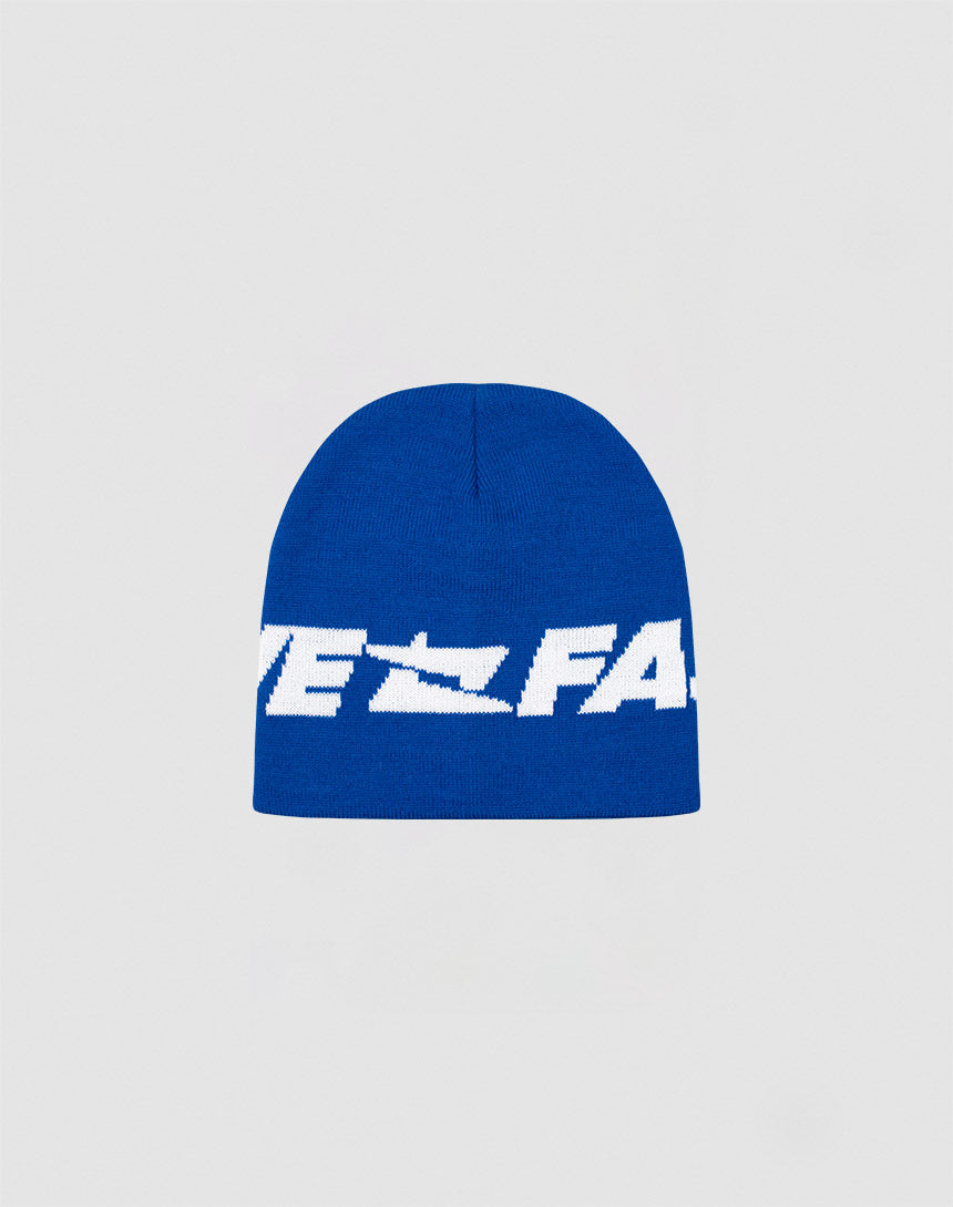 The Live Fast Jacquard Beanie by LIVE FAST DIE YOUNG is a blue knit polyacryl hat with bold white Logo Strick text across the front, shown on a plain light gray background. Style code: LF2410-16488.| plain
