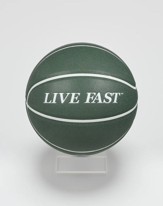 A dark green Live Fast Basketball by LIVE FAST DIE YOUNG, featuring bold white LIVE FAST lettering and white stripes, displayed on a clear stand against a plain white background.| plain 