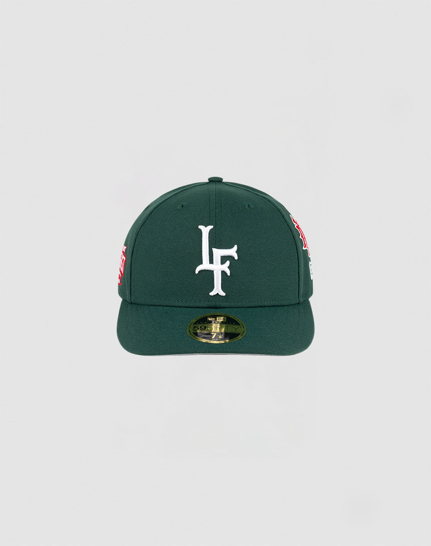The LFDY x NEW ERA 59FIFTY Low Profile by LIVE FAST DIE YOUNG is a dark green fitted cap with a flat brim, large white LF logo on the front, side patches, and a gold sticker on the brim. 