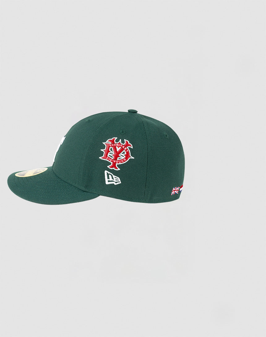 The LFDY x NEW ERA 59FIFTY Low Profile Cap by LIVE FAST DIE YOUNG features a dark green design, red and white side logo, small New Era icon, UK flag on the back, and gold sticker on the flat brim.