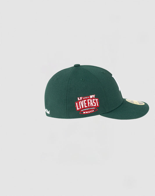 The LFDY x NEW ERA 59FIFTY Low Profile by LIVE FAST DIE YOUNG is a dark green low profile fitted cap with a white NY logo, red Live Fast patch, gold brim sticker, shown on a plain light gray background.
