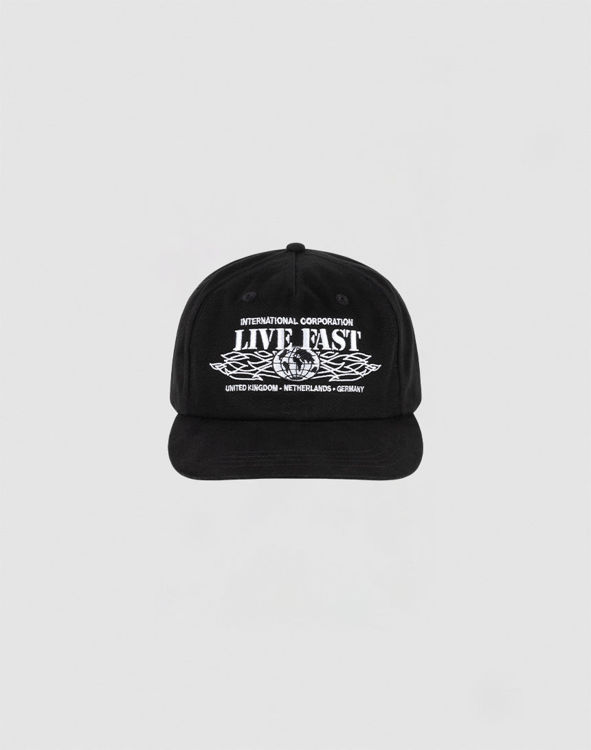 The Live Fast Corporation Cap by LIVE FAST DIE YOUNG is a black, 100% cotton unstructured 5-panel hat with multi-logo white text and graphics reading INTERNATIONAL CORPORATION LIVE FAST above stylized wings and UNITED KINGDOM - NETHERLANDS - GERMANY below.| plain
