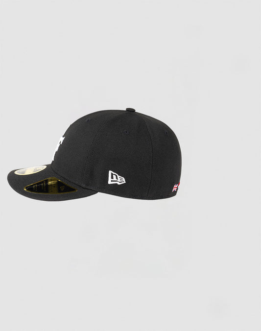 The LFDY x NEW ERA 59FIFTY Low Profile cap by LIVE FAST DIE YOUNG is shown from the side in black, featuring a white embroidered NEW ERA logo and a gold sticker on the flat brim against a plain light gray background.